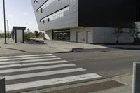 a white and black building with a crosswalk in front of it on a sunny day