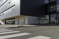 a white and black building with a crosswalk in front of it on a sunny day