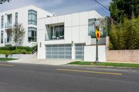 white house with garage and attached elevator on an empty street with trees around it and one yellow car in front