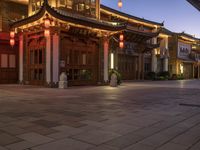 the illuminated entrance to an asian styled building at night with lanterns on it's sides