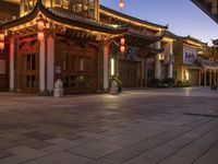 the illuminated entrance to an asian styled building at night with lanterns on it's sides