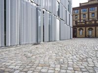 two people are walking down a cobble stone street while two buildings have closed them