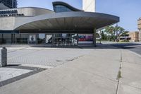 a person sitting at the bench in front of a mall that is empty of people