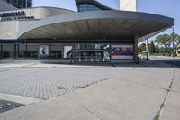 a person sitting at the bench in front of a mall that is empty of people