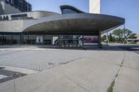 a person sitting at the bench in front of a mall that is empty of people