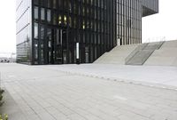 an open courtyard with stairs leading to an entrance that has windows, surrounded by a stone floor