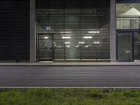 a man on his skateboard outside a building with doors that shut out and no people on the sidewalk