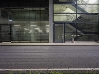 a man on his skateboard outside a building with doors that shut out and no people on the sidewalk