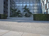 a building on an empty street with lots of glass windows on the buildings, and people walking in front of it