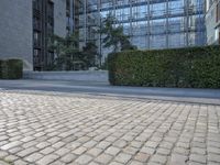 a building on an empty street with lots of glass windows on the buildings, and people walking in front of it