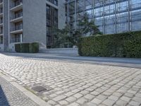 a building on an empty street with lots of glass windows on the buildings, and people walking in front of it