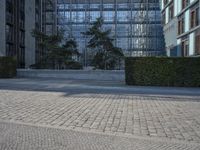 a building on an empty street with lots of glass windows on the buildings, and people walking in front of it