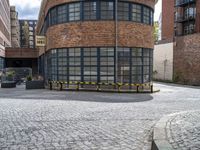 a brick and iron building sitting on the side of a road next to a black and yellow bench