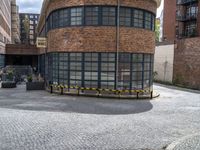 a brick and iron building sitting on the side of a road next to a black and yellow bench