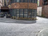 a brick and iron building sitting on the side of a road next to a black and yellow bench