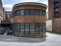 a brick and iron building sitting on the side of a road next to a black and yellow bench