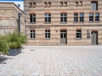 a building with a brick walkway next to green plants in planters on the ground