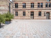 a building with a brick walkway next to green plants in planters on the ground