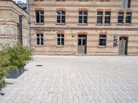 a building with a brick walkway next to green plants in planters on the ground