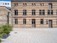 a building with a brick walkway next to green plants in planters on the ground