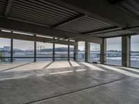 a empty building by some water and some buildings with an overhead roof that has a mesh screen