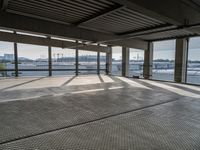 a empty building by some water and some buildings with an overhead roof that has a mesh screen