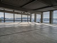 a empty building by some water and some buildings with an overhead roof that has a mesh screen