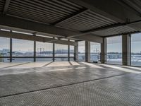 a empty building by some water and some buildings with an overhead roof that has a mesh screen