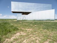 a mirror that is on top of grass and dirt in the ground near a field