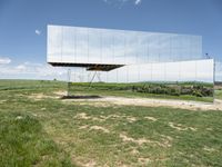 a mirror that is on top of grass and dirt in the ground near a field