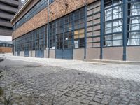 there is an open window on this brick building with concrete curb in front of it