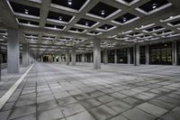 there is a courtyard inside a building with columns and ceiling lights on the floor and a large concrete structure