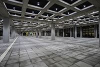 there is a courtyard inside a building with columns and ceiling lights on the floor and a large concrete structure