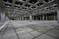 there is a courtyard inside a building with columns and ceiling lights on the floor and a large concrete structure