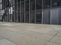 a sidewalk with two white fire hydrants outside of a building with windows in it