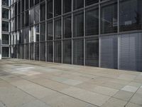 a sidewalk with two white fire hydrants outside of a building with windows in it