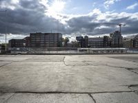 a parking lot with a road and a large building in the back ground and a large construction crane in the background