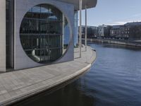 an open area with a water way that goes around it, and a circular building near by