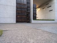 the side of a concrete building that has a gate on top of it next to a sidewalk