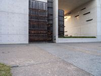 the side of a concrete building that has a gate on top of it next to a sidewalk