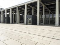 a man walks in front of a modern building with pillars that extend both sides of the walkway