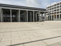 a man walks in front of a modern building with pillars that extend both sides of the walkway