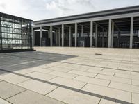 a man walks in front of a modern building with pillars that extend both sides of the walkway