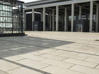 a man walks in front of a modern building with pillars that extend both sides of the walkway