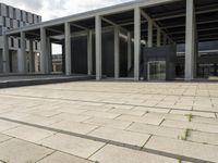 a man walks in front of a modern building with pillars that extend both sides of the walkway