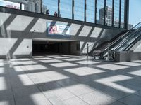 the walkway outside of the building is covered with large windows and stairs next to it