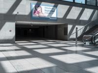 the walkway outside of the building is covered with large windows and stairs next to it