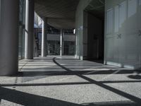 a sidewalk with several columns and an outside bench that has a curved design on it