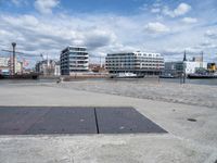 an empty cement sidewalk with some buildings in the background on a sunny day by the water