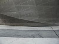 a person walking through a courtyard with an umbrella on the floor by a wall and curved roof